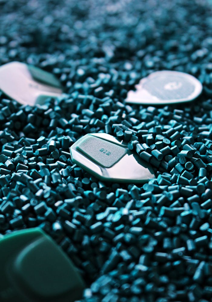 Detailed view of green guitar picks surrounded by textured plastic pellets.